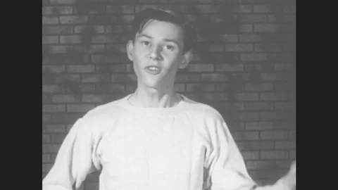 1950s: Young man talks. Young man rides bicycle to house under construction. Stock Footage