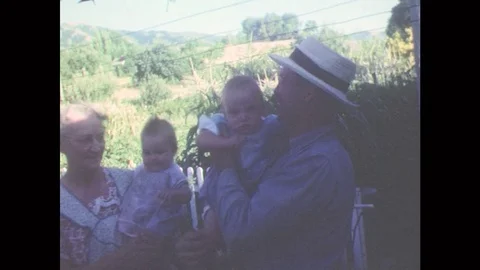 1950s: Younger Man In Straw Boater Takes A Baby From Older Woman. Straw Boater Stock Footage