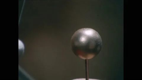 1950s:Pith ball hangs next to brass ball. Pith ball repulsed from brass ball. Video stock 229570688