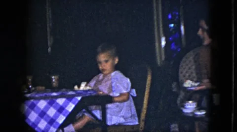 1951: a cute baby girl is sitting in the dinning table chair and watching Stock Footage