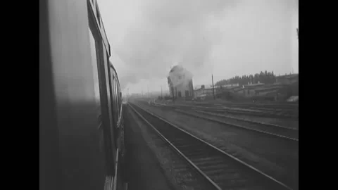 1951 - Filmed from the back of a window a train is riding past landscape and a Stock Footage 232892441