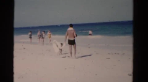 1951: a shirtless man on the beach shaking sand from a towel FLORIDA Stock Footage