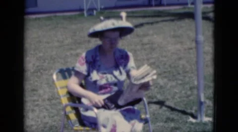 1951: women reading newspaper by clothesline in funny broad brimmed hat FLORIDA Stock Footage