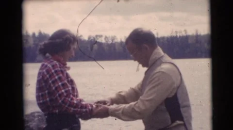 1953: man teaching a young woman how to cast a fishing line in the water Stock Footage