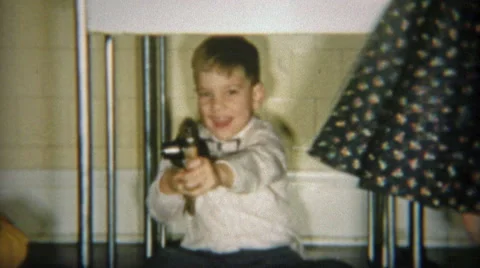 1954: Boy Recklessly Pointing Toy Guns and Bossing Around Playmate Stock Footage 56226193