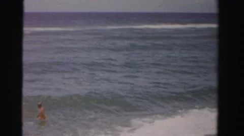 1955: working hard to keep their footing in the crashing waves of the ocean. Stock Footage