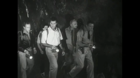 1957 - Scientists use flashlights to explore a cavern and one of them loses a Stock Footage 129450947