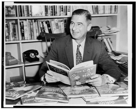 1957. Theodore (Ted) Geisel (Dr. Seuss) seated at desk covered with his books Stock-Fotos