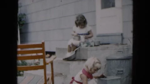 1957: two little girls playing house in their yard by cement steps Stock Footage
