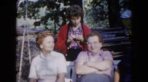 1960: ladies sitting on a bench swing talking and smiling to each other Stock Footage