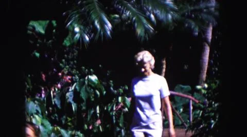 1960:MIAMI FLORIDA USA.Mujer Cruza Puente De Bambú Rojo Y Muestra A Niña Flores Stock Photos