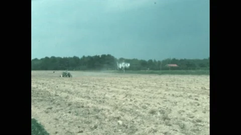 1960s: 1960s American tractor pulls plough across field. Farmer ploughs up field Stock Footage 194187215