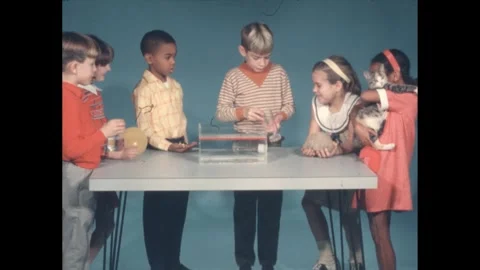 1960s: 6 kids hold objects at table, boy pulls stopper from glass cylinder, Stock Footage 240679156