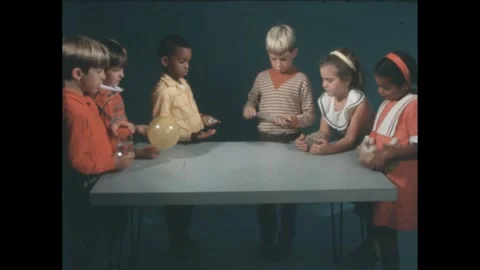1960s: 6 kids hold objects around table, boy pulls apart glass syringe, hands Stock Footage 240679269