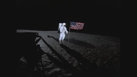 1960s: Astronaut on moon adjusts American flag.  Man runs across moon.  Men Stock Footage