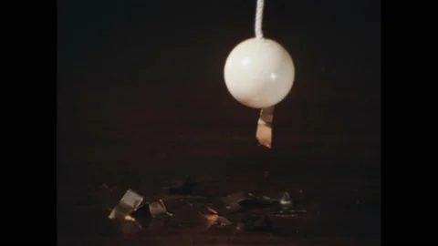 1960s: A ball on a string picks up metal shavings. A hand ties a string to a Stock Footage 189934209