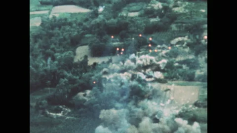 1960s: Bombs fall through air. Explosions on ground. Stock Footage 143365568