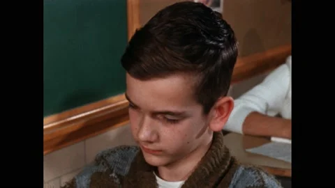 1960s: book on table in classroom. Boy thinks about maths problem. Hand holds Stock Footage 219965682