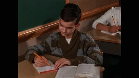 1960s: boy adds up numbers during maths lesson. Coronet film slate in hand. Girl Stock Footage 219965694