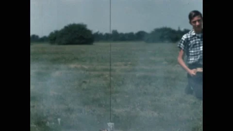 1960s: Boy launches a model rocket in a field. The base of a model rocket on a Stock-Footage 188532434