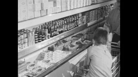 1960s: Boy places two boxes of chop suey in a shopping cart. Man pushes the cart Stock-Footage 250702403