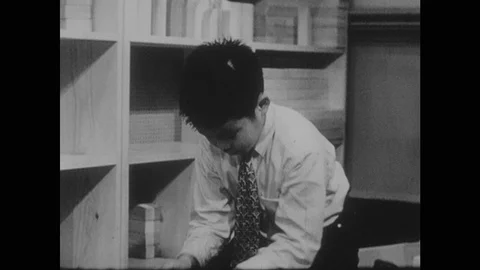 1960s: Boy playing with string. Boy takes sticks out of toy truck. Boy wraps Stock Footage 124338279
