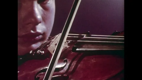 1960s: Boy Pulls Bow Back and Forth Over the Violin Stock Footage 74723029
