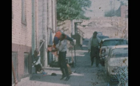 1960s: Boy runs down sidewalk. Man wrestles with boy near apartment. Woman in Stock Footage 146601309