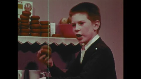 1960s: Boy stacks piles of donuts, talks. Men talk, shake hands. Machine spits Stock Footage 119503989