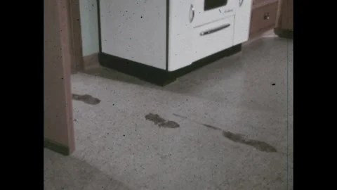 1960s: Boy steps in a mud puddle. He runs into a kitchen, leaving muddy Stock Footage 289208710