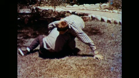 1960s: boys play fight in garden. Lady works at desk. Lady turns off desk lamp. Stock Footage