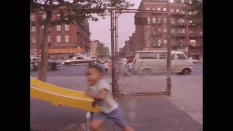 1960s: Boys slide down slides in a playground. Women sit on a bench with babies Vidéo 220240894