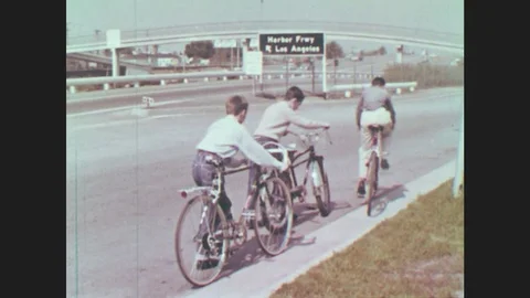 1960s: Boys start to ride their bikes. Astronaut lays in machine and practices. Stock Footage