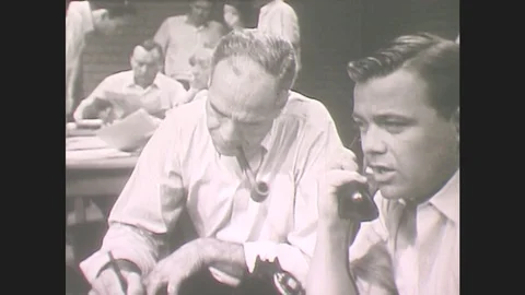 1960s: Bustling Office. Man Smokes Pipe, Writes. Man Talks On Phone. Group Of Stock Footage