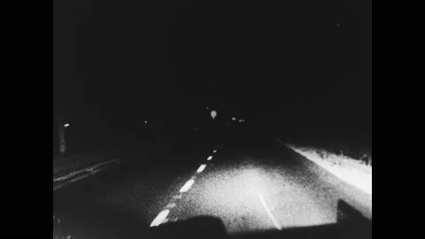 1960s: car driving down road at night then swerves and hits two people Stock Footage 130394945