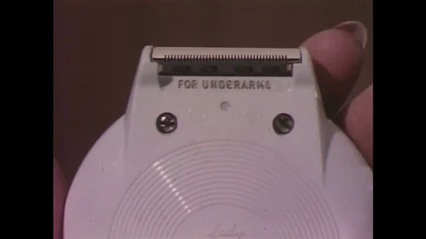 1960s: Close up of electric razor / Woman shaves underarm / Close up of electric Stock Footage