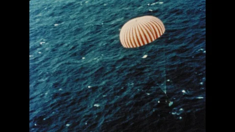 1960s: Command module descends toward ocean with parachute. Command module Video stock 101665748