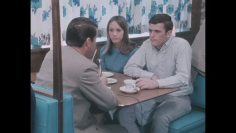 1960s: Couple sitting at a restaurant table, interviewer asking questions. 스톡 동영상 244537614