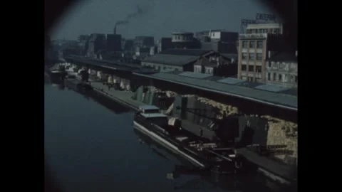 1960s: Crane unloads barge on river near industrial section of city in France. Stock Footage 283926765