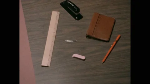 1960s: Cups, toy tools, plastic toys and office supplies sit on tabletop. Six Stock Footage 238835110