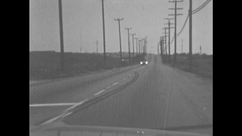 1960s: Driving down road at night, oncoming car on other lane. Man driving Stock Footage 81870076