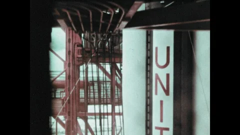 1960s: Elevator moves down launch tower.  Men work on rocket. 動画素材 104881051