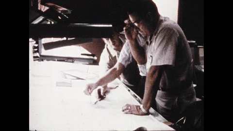 1960s: Engineers look at plans on drafting table. Plane flies over boat in Stock Footage 106412017
