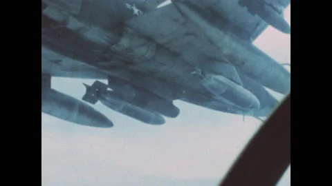 1960s: Explosion on ground. Underside of fighter jet. Man uses pointer to point Stock Footage 143365972