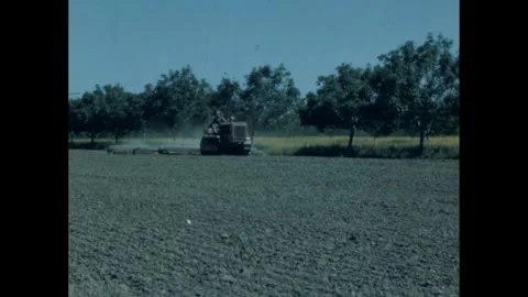 1960s: Farmer on tractor pulls device that sprays the field. Stock Footage 290244485