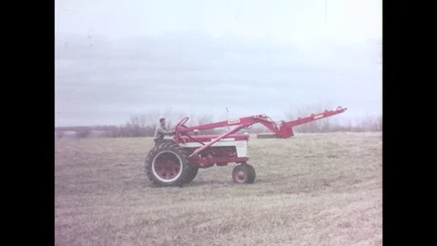 1960s: Farmhand drives baler. Baler lifts row of bales. Farmhand drives tractor Stock Footage