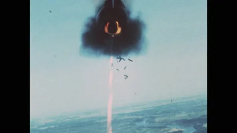 1960s: Fighter jet fires ammunition. Explosions on ground. Plane drops missile. Stock Footage 143365608