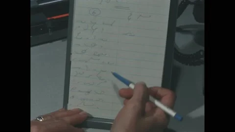 1960s: Fingers hold a notepad with scribbles on it, a pen scrolls down the page, 스톡 동영상 171187691