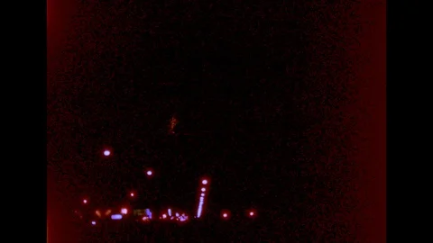 1960s: Fireworks explode in night sky over street lights. Stock Footage 112013745