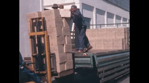 1960s: Forklift delivers stack of cardboard boxes to back of truck. Group of men 스톡 동영상 258142875